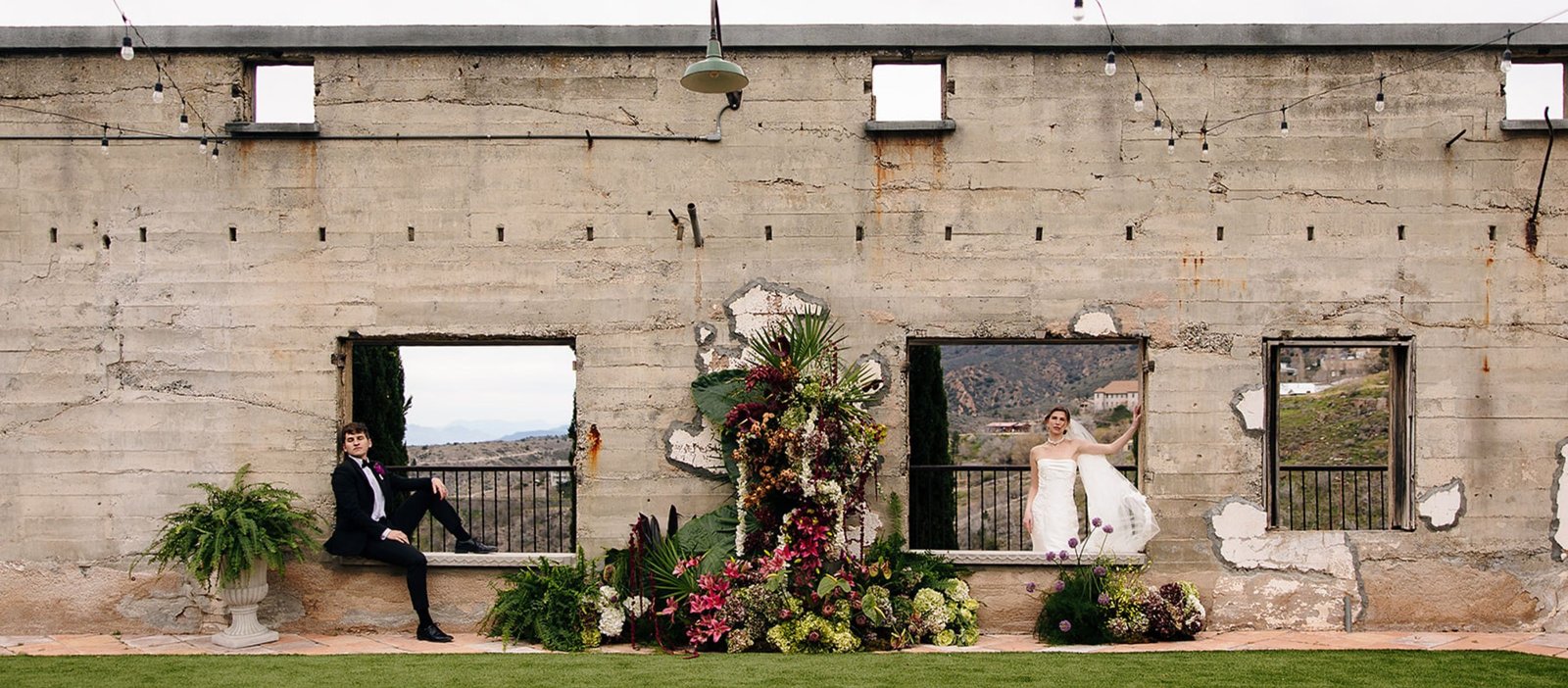 Bride and groom framed by florals in an editorial venue portrait